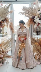 Stunning Indian bride in her dress on her wedding day with soft glam makeup and a sleek bun.